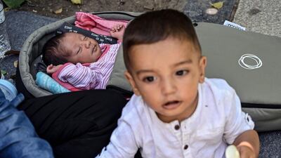 A boy sits by his 16-days old sister as refugee families camp at Victoria square in central Athens, Greece. Around 100 mostly Afghan refugees have been camping in a square in recent days under temperatures exceeding 30 degrees Celsius (86 Fahrenheit) after arriving from island's camps. AFP