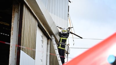 A firefighter works on a broken roof near Barfleur, north-western France. AFP