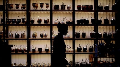 Paola Garcia walks past herbal "mate" mugs at the shop where she works in Buenos Aires, Argentina. AP Photo