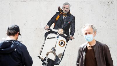 Two men stop by a mural depicting new AS Roma manager Jose Mourinho riding a Vespa on a wall in Rome. Reuters