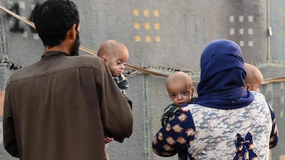 A man and woman carry malnourished children at a camp for Syrians displaced by conflict near the town of Deir Al Ballut by Syria's border with Turkey in the northwest of the Aleppo province, September 28. Rami Al Sayed/ AFP