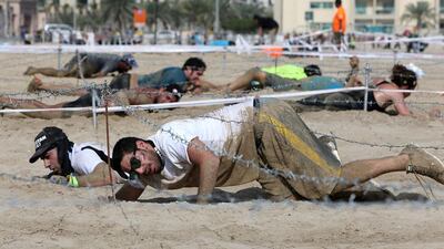Runners crawl under the barbed wire.
