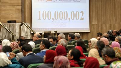 People sit near a screen displaying the population count at the Egyptian Ministry of Planning, in Cairo, Egypt. EPA