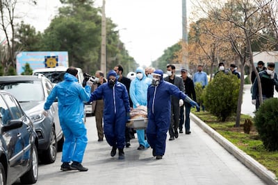 Men wearing protective gear carry the body of Fatemeh Rahbar, a lawmaker-elect from Tehran constituency, who died on Saturday after being infected with the new coronavirus at Behesht-e-Zahra cemetery outside Tehran. Fars News Agency via AP, file
