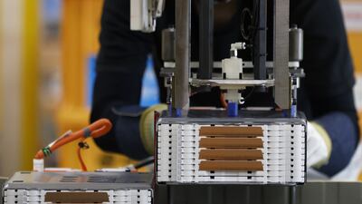 A worker installs a stack of lithium-ion batteries onto a battery pack for a kei electric vehicle. Bloomberg