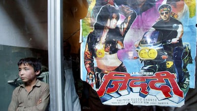 A boy stands next to a Bollywood poster, as he waits for a film to start Cinema Park in 2002 in Kabul, Afghanistan. Getty Images