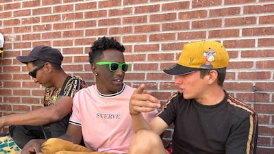 Paolo, 21, on the right, sits with other migrants outside the Sacred Heart Church in El Paso