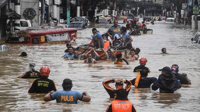 Rescuers pull a rubber boat carrying residents through a flooded street after Typhoon Vamco hit in Marikina. AFP
