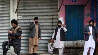 An Afghan security personnel (L) stands along with Sikhs near the site of an attack to a Sikh temple in Kabul. AFP