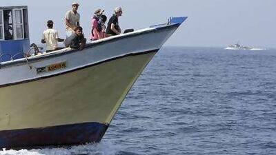 With an Israeli navy ship in the background, members of the "Free Gaza" group sail on a fishing boat off the Gaza Strip.