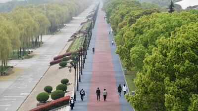 People wearing face masks walk at a riverside park in Wuhan of Hubei province. Reuters