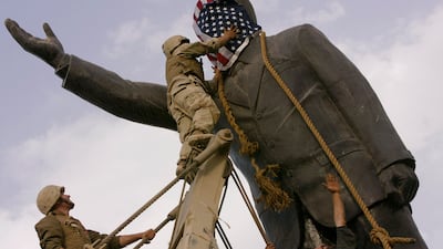 A US Marine uses an American flag to cover the face of a statue of Saddam Hussein before pulling the monument down in Baghdad on April 9, 2003. AP