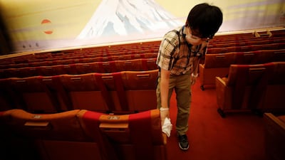 A member of staff wearing a protective mask disinfects a seat at the Kabukiza Theatre. Reuters
