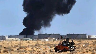 Libyan rebels adjust an anti-aircraft gun as smoke from a damaged oil facility darkens the sky in Ras Lanuf, Libya. Getty Images