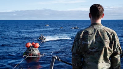 A member of the Air Force watches as the Orion capsule is towed towards the USS Portland. EPA