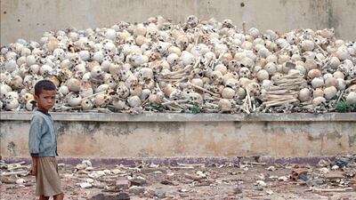 A Cambodian boy stands in front of a platform covered with human skulls at a killing field discovered in Trapeang Sva Village in 1995. AP Photo / Richard Vogel