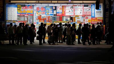 People stand in front of an electronics store in Tokyo. Japan's sluggish economy has prompted the prime minister Shinzo Abe to delay a sales tax hike by more than two years. Toru Hanai/Reuters