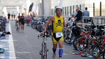 An athlete dismounts his bicycle and moves onto the running portion of the Tri Yas. Sarah Dea / The National