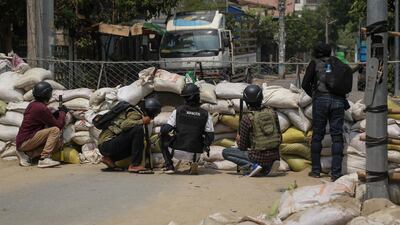 Protesters take cover during a protest against the military coup in Mandalay. EPA