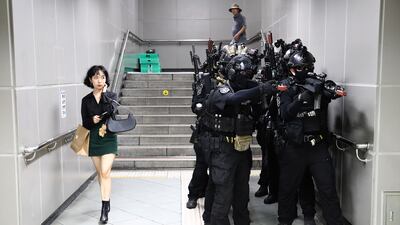 A woman passes soldiers taking part in an anti-terrorism and anti-chemical attack drill in Seoul, South Korea. Getty Images