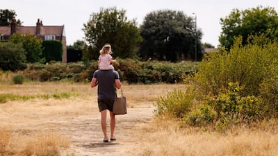 People walk through dry grass across Leyton Flats in east London. EPA