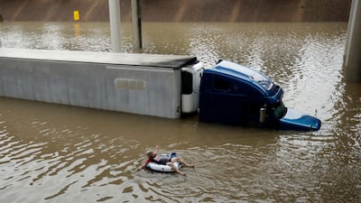 After helping the driver of the submerged truck get to safety, a man floats on the freeway flooded by Hurricane Harvey near downtown Houston. Charlie Riedel / AP Photo
