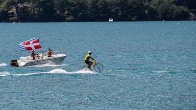 A man wearing a yellow jersey performs water skiing on a bicycle, on the Lake of Annecy during the 10th stage of the Tour de France between Annecy and Le Grand-Bornand. Jeff Pachoud / AFP