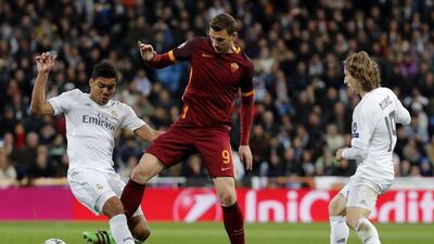 Real Madrid midfielders Casemiro, left, and Luka Modric fight for the ball with Roma striker Edin Dzeko. Javier Lizon / EPA