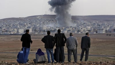 Smoke from an explosion rises over the Syrian city of Kobani as people on the Turkish side of the border look on. Sedat Suna / EPA