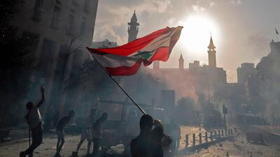 A Lebanese protester waves the national flag during clashes with security forces in downtown Beirut on August 8, following a demonstration against a political leadership they blame for the Beirut explosion that killed at least 158 people and disfigured the capital. AFP