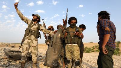 Rebel fighters pose for a picture with the remains of a downed regime warplane near the militant-held town of Khan Sheikhun in the south of Idlib province. AFP