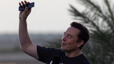 Elon Musk raises his phone towards the sky at an event in August. Reuters