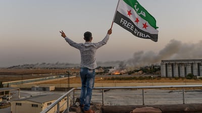 A man waves a Syrian opposition flag reading "Free Syria" in Akcakale as smoke rises in the background from the Syrian border city of Tal Abyad seized by Turkish forces and their proxies. AFP