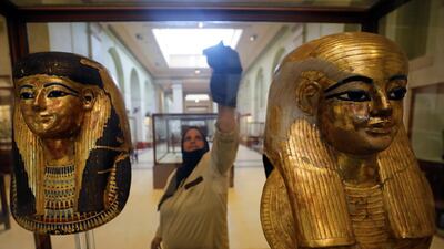 A worker cleans the display glass of ancient pharaoh masks as tourists visit the Egyptian Museum at Tahrir Square after its reopening in Cairo, Egypt. Reuters