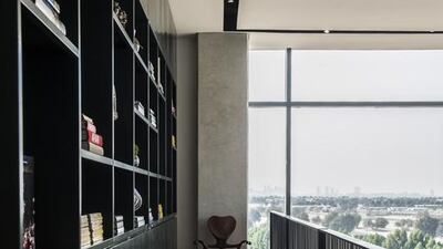 An indoor balcony with a bookshelf running along its length looks over the living room, but also offers expansive views of the landscape beyond. Courtesy KOA