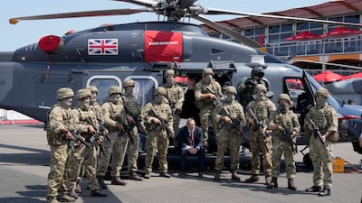 Soldiers pose beside a Leonardo helicopter. AP