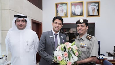 Colonel Ali Al Hammadi (right) congratulates Anoop Moopen (middle) as he receives his gold card visa.