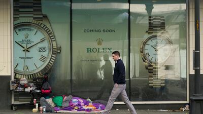 A person sleeps beside a shopping cart as a pedestrian walks past, in downtown Seattle, US. AP