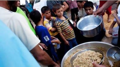 Syrian refugees wait to receive food from a makeshift kitchen in a temporary refugee camp near the Al-Salama crossing between Syria and Turkey.