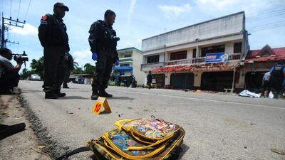 A child's backpack lies on the ground as members of a Thai bomb squad inspect the site of a motocycle blast in front of a school by suspected separatist militants in the Takbai district of Thailand's restive southern province of Narathiwat on September 6, 2016. Madaree Tohlala/AFP
