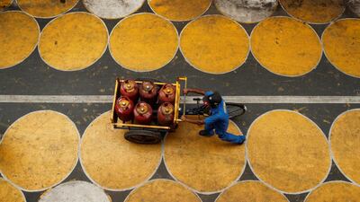 A man pushes a cart filled with liquefied petroleum gas (LPG) cylinders on a street painted with circles for people to maintain social distancing after a few restrictions were relaxed during an extended lockdown to slow the spread of the coronavirus in Mumbai, India. Reuters