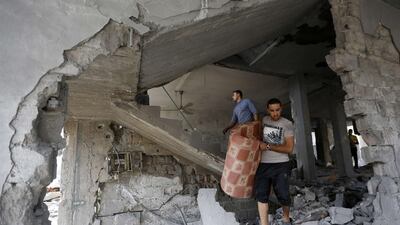 Palestinians inspect the rubble of their building that was partially destroyed following an Israeli airstrike. AFP / Mohammed Abed