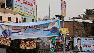 Men work on rooftops to fix banners for parliamentary candidates in Cairo. Egypt is using the Hare election method.