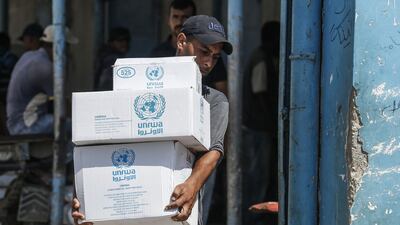 A Palestinian man transports boxes of food outside an aid distribution centre run by the United Nations Relief and Works Agency (UNRWA) in the central Gaza Strip refugee camp of Bureij. AFP