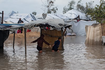 Displaced Palestinian children make their way through a flooded street. EPA