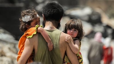 A man carrying two children while fleeing from the Old City of Mosul on July 2, 2017. A new study by Save the Children shows that despite their escape, children in Mosul continue to suffer psychological damage from living under the terror of ISIL. Ahmad Al Rubaye/AFP Photo