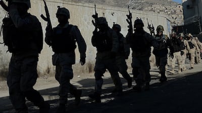 In this photo taken on January 21, 2013, Afghan commandos walk down a road near the Kabul police headquarters building after a clash between Afghanistan forces and Taliban fighters in Kabul. Shah Marai / AFP