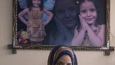 Rawya abu Jom’a nearly one year after last summer’s war , sits under a picture frame showing photographs of her 4 year-old sister Rehav who was killed together with her two aunts when their apartment in Gaza City was hit by an Israeli airstrike. Although the horrific shrapnel wounds have healed on her face , the memories of the war give her flash backs and nightmares still one year later .She is unable to use her right hand because the nerves and bones were badly damaged . She spent 4 months being treated in Jordan following the war but still needs further surgery . She was supposed to start her first year of university but could not because she can not write. Heidi Levine for The National