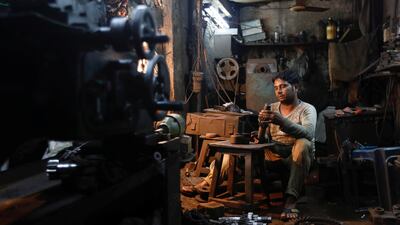 A man repairs gear parts used in automobiles inside a workshop at an industrial area in Mumbai, India. Small businesses have been struggling with the new tax. Danish Siddiqui/Reuters