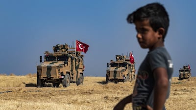 A Syrian boy watches as Turkish military vehicles, part of a US military convoy, take part in joint patrol in the Syrian village of Al Hashisha on the outskirts of Tal Abyad town along the border with Turkey, on October 4, 2019. AFP